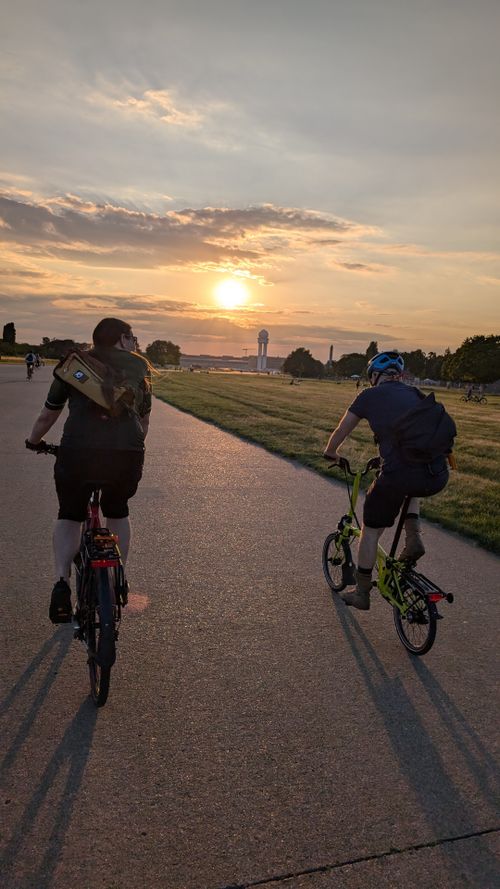 Menschen fahren über das Tempelhofer Feld dem Sonnenuntergang entgegen.